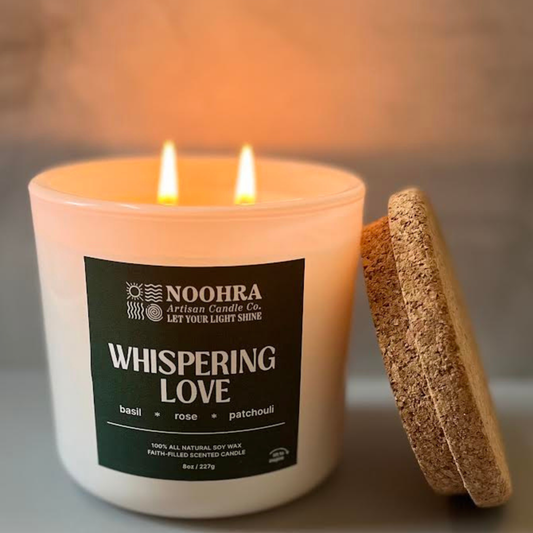 A candle with a label that says Whispering Love